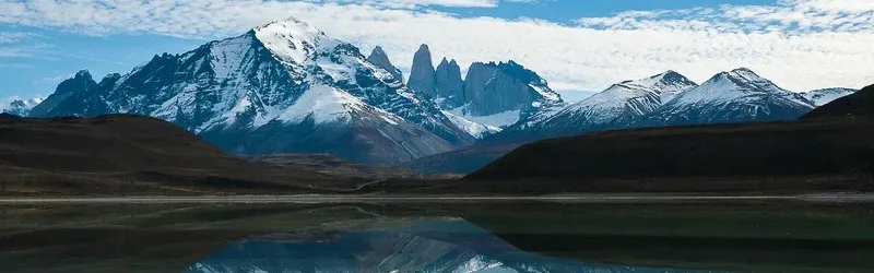 A wide view of the turquoise Laguna Amarga reflecting the granite towers of Torres del Paine.