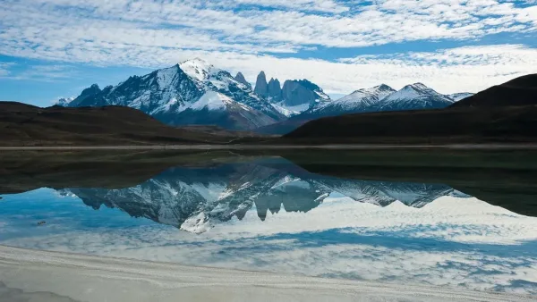The distinct white salt crust lining the shores of Laguna Amarga under a clear Patagonia sky.