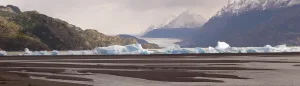 Una amplia playa de guijarros en Lago Grey, donde enormes icebergs azules llegan a la orilla procedentes del glaciar cercano.