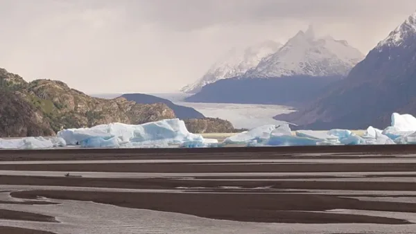 Una amplia playa de guijarros en Lago Grey, donde enormes icebergs azules llegan a la orilla procedentes del glaciar cercano.