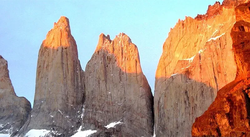 A panoramic view of the three granite peaks of Torres del Paine rising above the turquoise glacial lagoon.