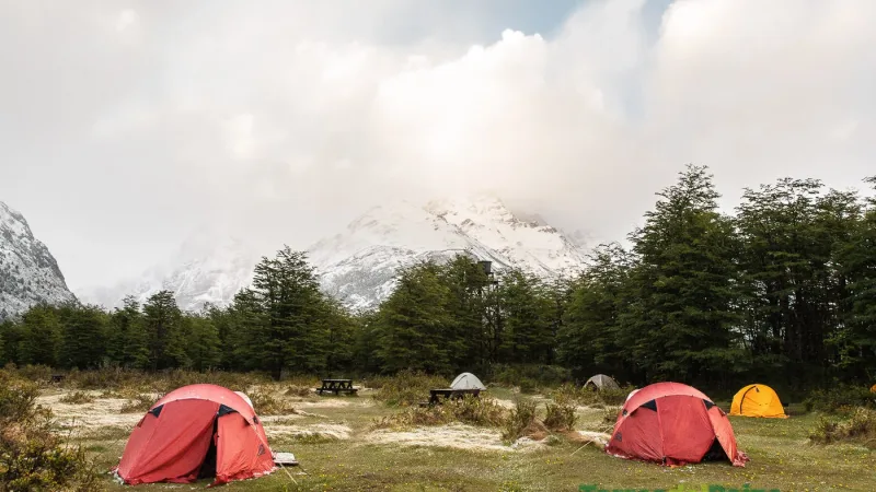 Expansive grassy campsite at Camping Dickson with views of the surrounding mountains and glaciers.
