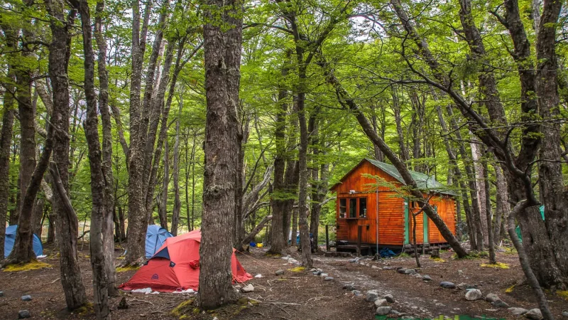 Hikers resting beside their equipment at the rugged Los Perros campsite surrounded by dense woodland.