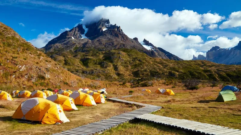 Amplios campos verdes en el Camping Paine Grande con vistas a las verticales paredes de granito del macizo.