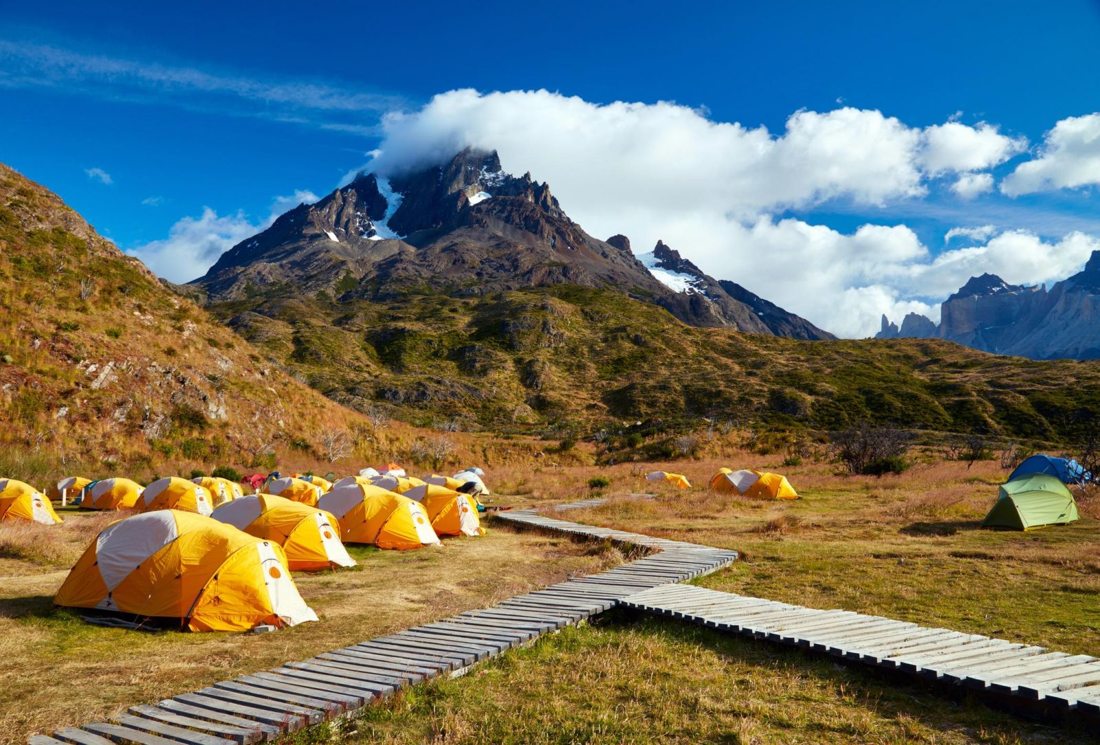 Amplios campos verdes en el Camping Paine Grande con vistas a las verticales paredes de granito del macizo.
