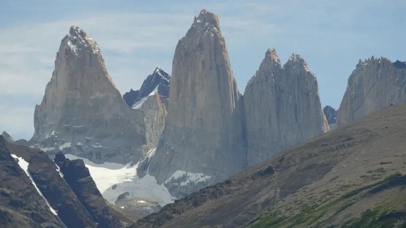 As três icônicas torres de granito erguem-se imponentes sobre uma lagoa glacial azul.