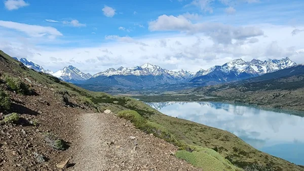A narrow hiking trail winding through the yellow pampa toward the Dickson valley.