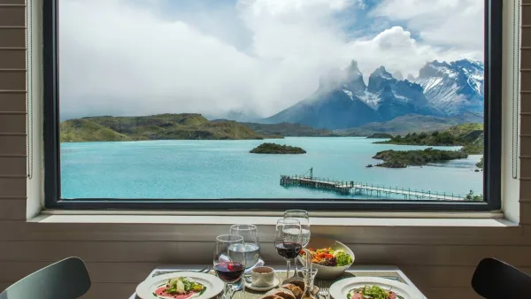 Un comedor luminoso y espacioso en el Hotel Explora, con detalles en madera local y vistas al macizo.