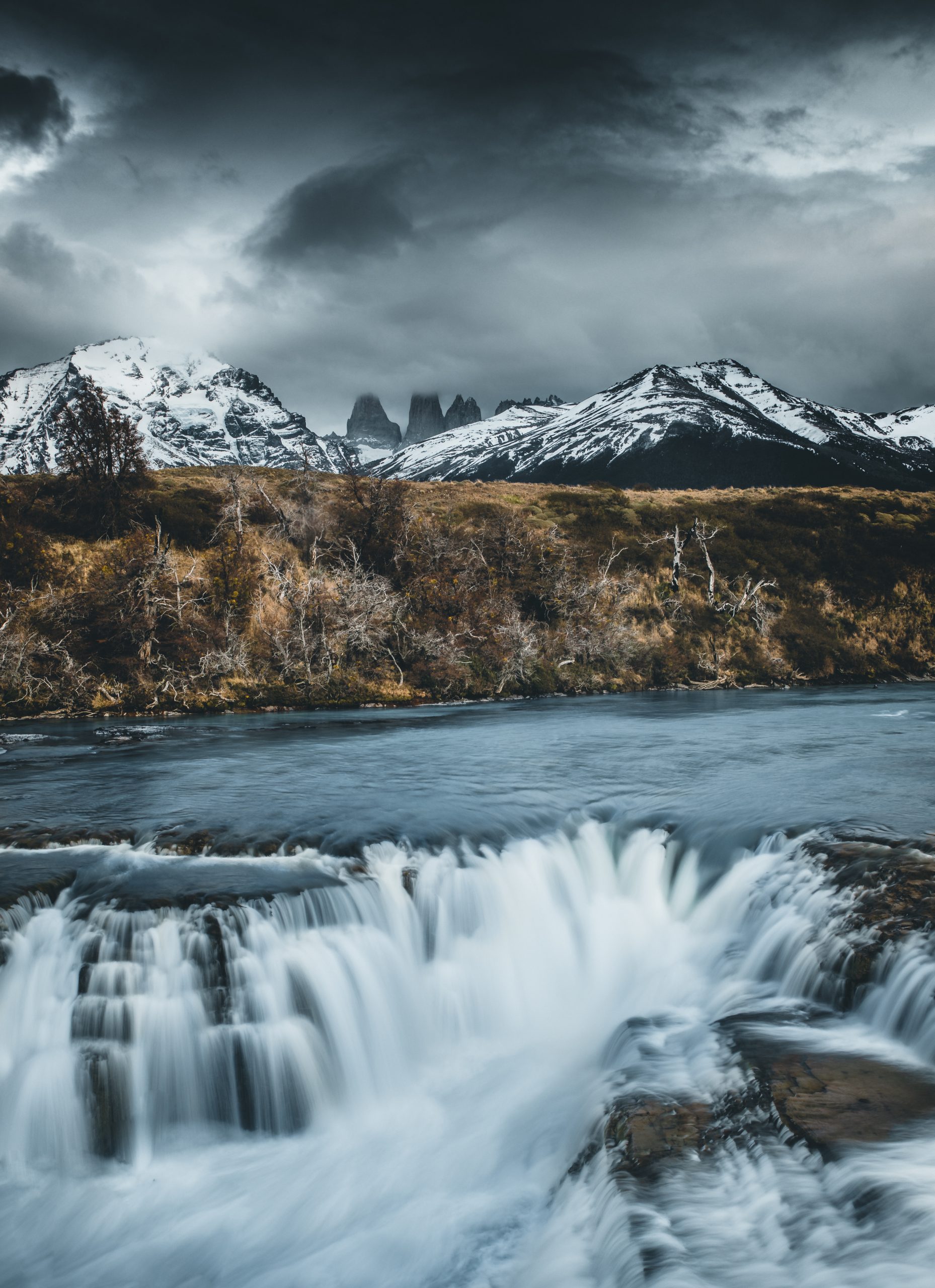 Uma vista panorâmica da Laguna Azul, de um azul profundo, rodeada pela vegetação dourada dos pampas e colinas acidentadas.