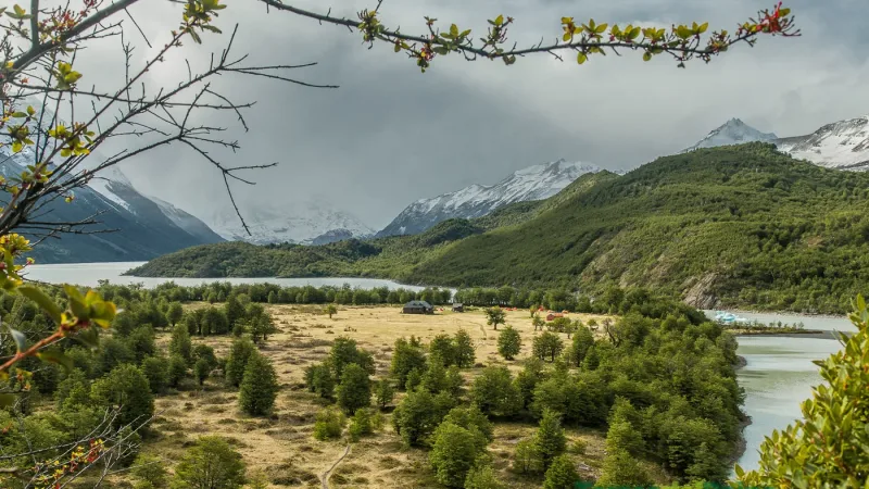 The wooden main building of Refugio Dickson nestled in a green valley near the glacier.