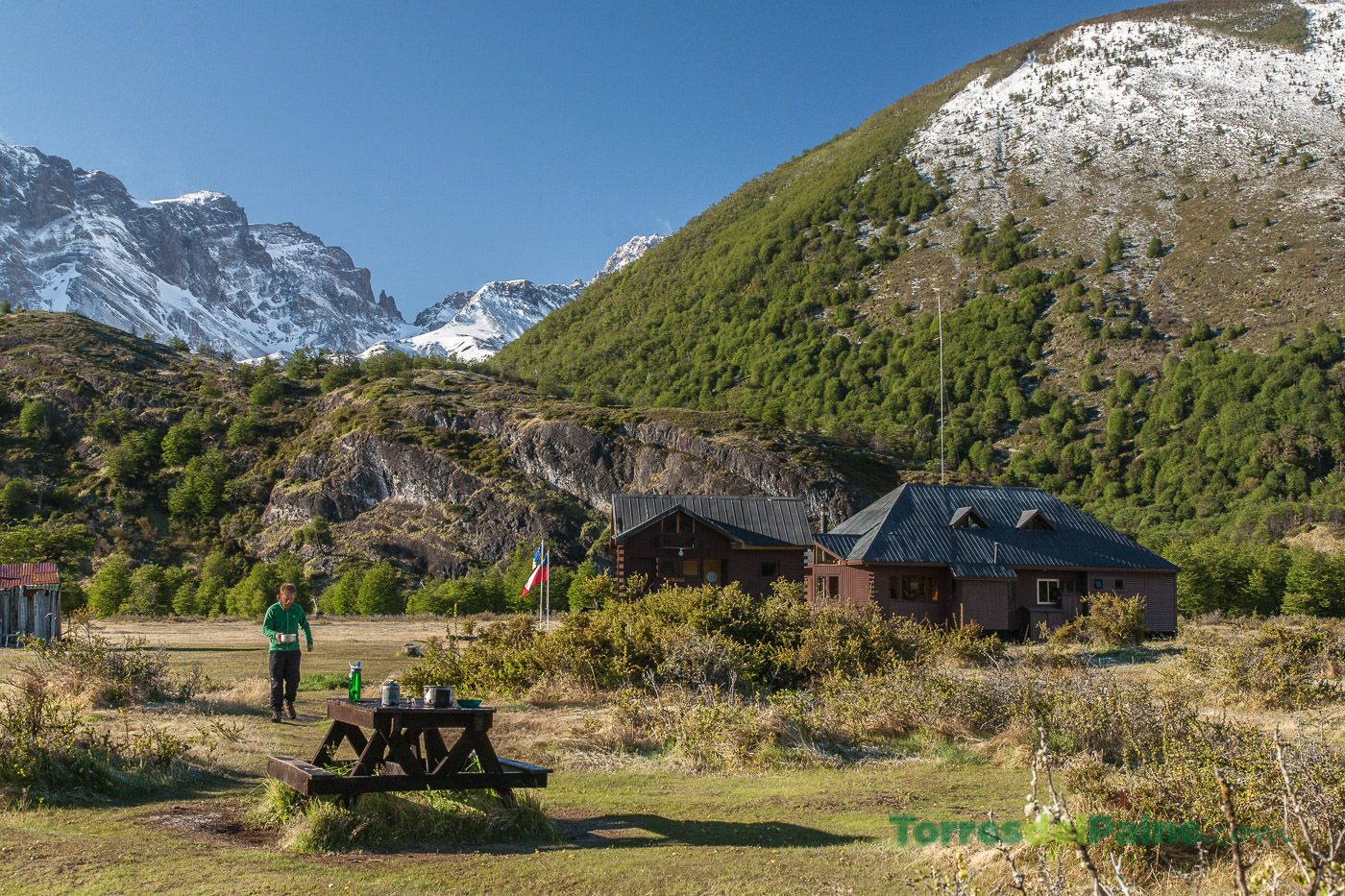 A cozy interior view of the common area at Refugio Dickson with wooden tables and mountain views.