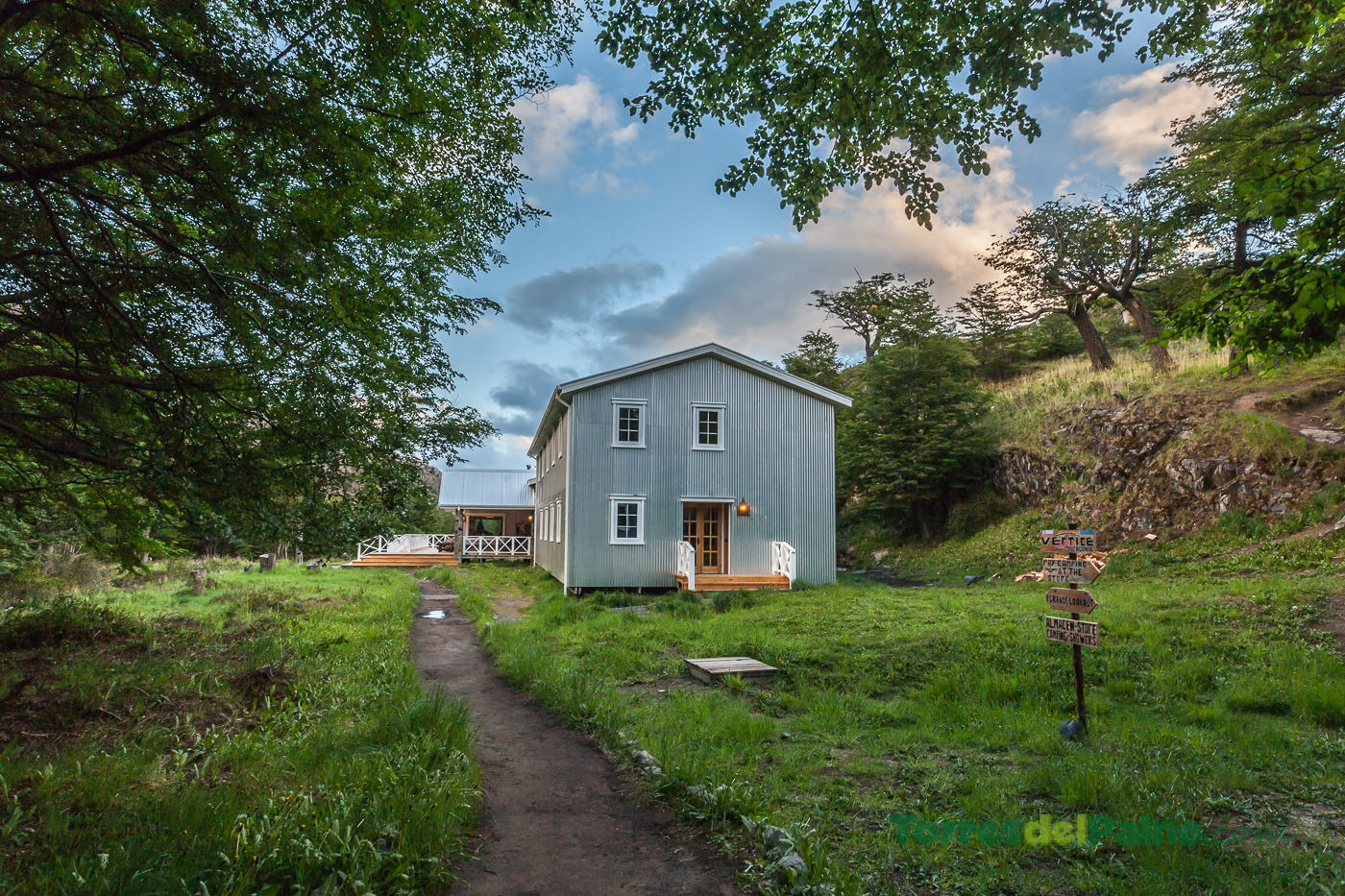 Passarelas de madeira serpenteiam entre as árvores, conectando as diferentes cabanas no acampamento Grey.