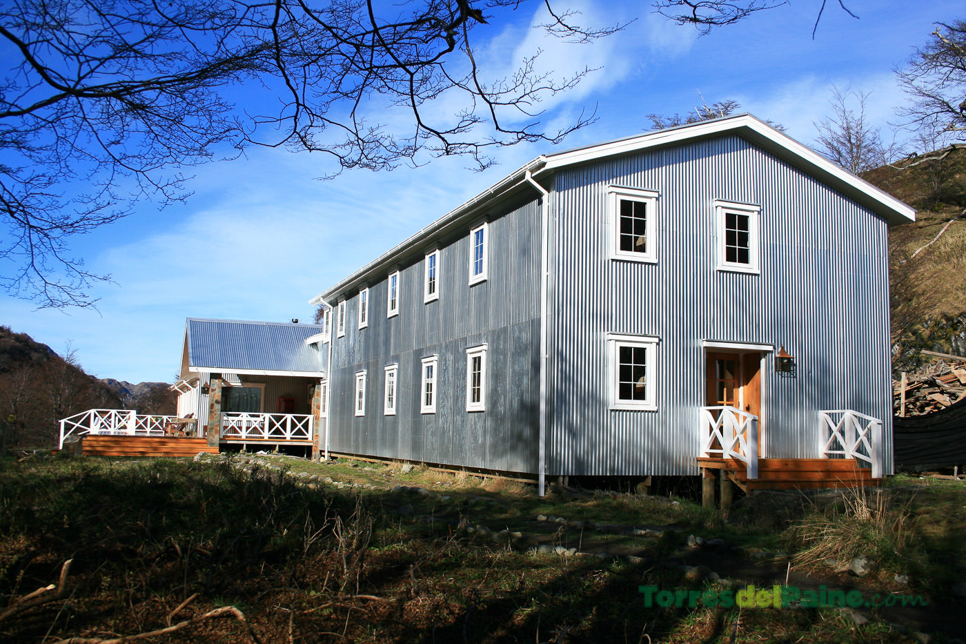 Um grupo de caminhantes compartilhando uma refeição no refeitório amplo e iluminado do refúgio Grey.