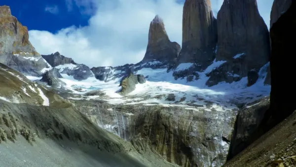The iconic granite towers of the Paine Massif reflected in a calm glacial lagoon.