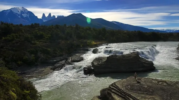 Water rushing over the rocks at Cascada Paine with the towers of the massif in the background.