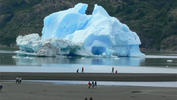 A wide view of Lake Grey dotted with floating blue icebergs from the nearby glacier.