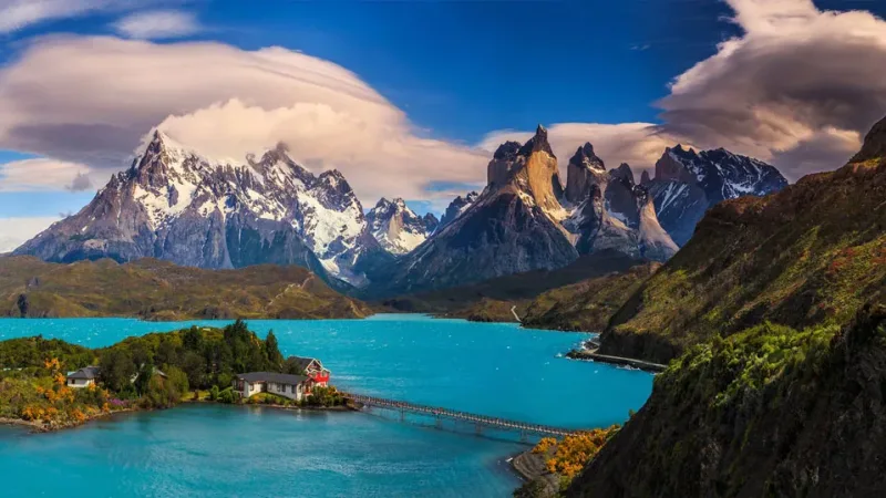 La emblemática fachada amarilla y marrón de Hosteria Pehoé contrastando con el azul del lago.