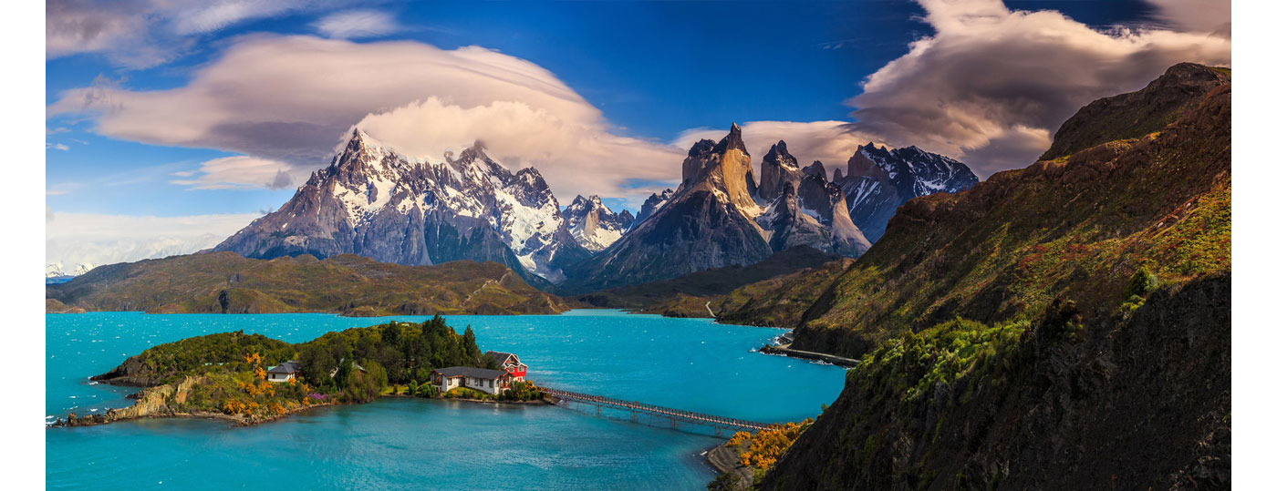 La emblemática fachada amarilla y marrón de Hosteria Pehoé contrastando con el azul del lago.