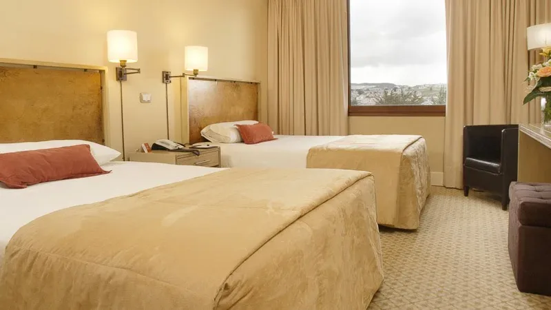 Quarto duplo sofisticado no Hotel Cabo de Hornos, com detalhes em madeira local e roupa de cama de alta qualidade.