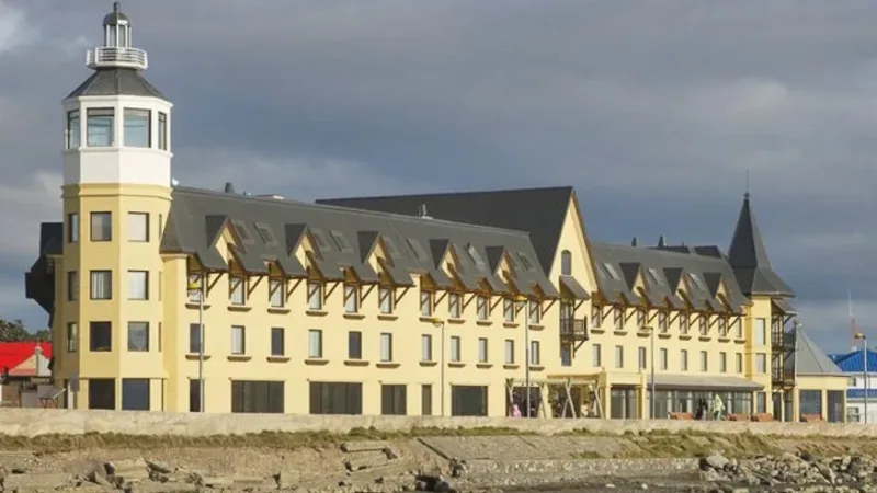 Exterior of Hotel Costa Australis in Puerto Natales with its signature blue and yellow architecture by the sea.