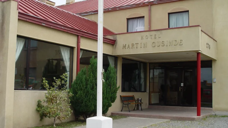 Duas camas de solteiro em um quarto de hóspedes no Hotel Martin Gusinde, demonstrando uma configuração simples e confortável.