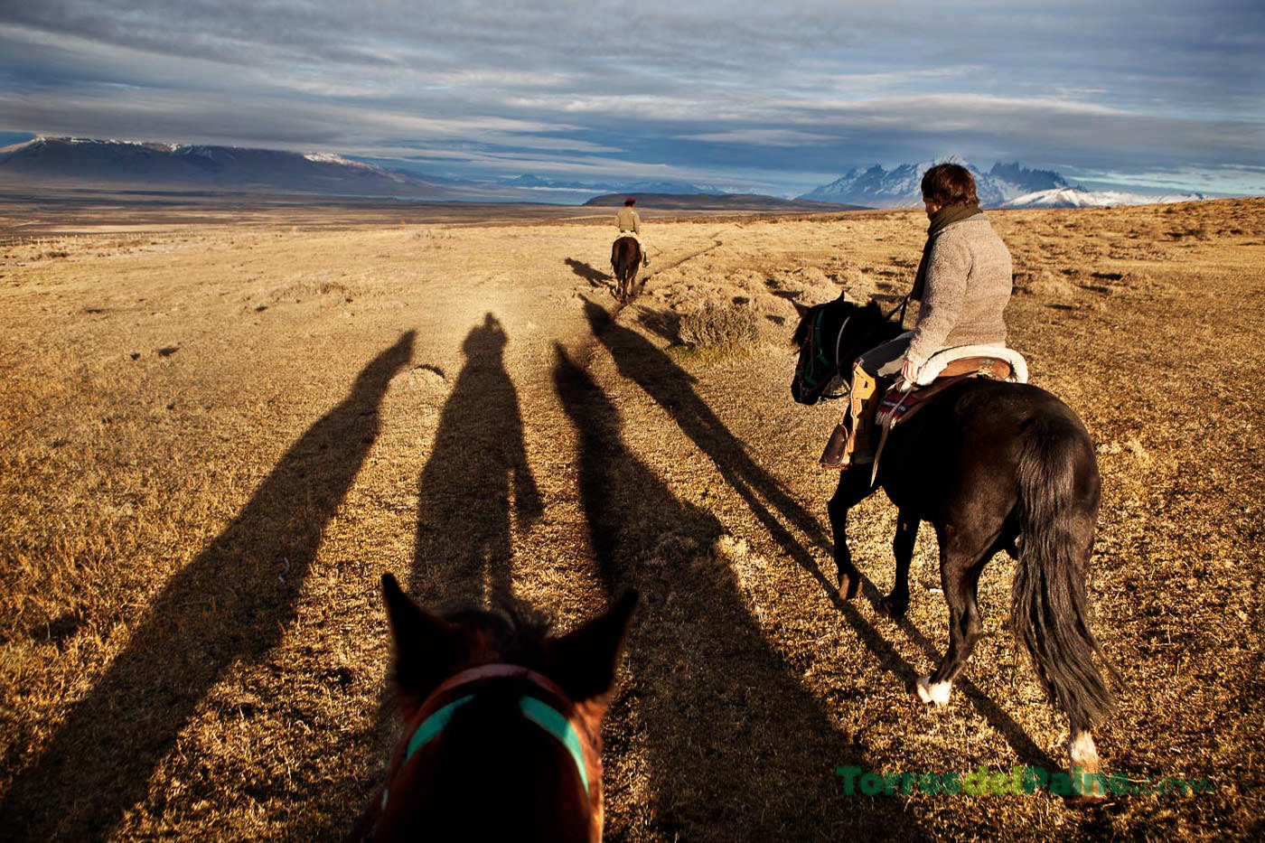 Um hóspede relaxando em um assento privativo junto à janela em seu quarto no Tierra Patagonia, assistindo ao pôr do sol.
