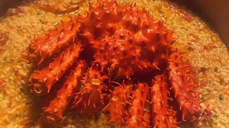 Centolla vermelha inteira sobre arroz caldoso com ervas, servida em panela, prato do restaurante La Cuisine em Punta Arenas