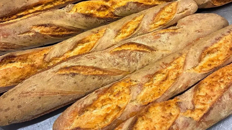Baguetes francesas recém-assadas com casca dourada e crocante sobre bancada de inox na La Cuisine, Punta Arenas
