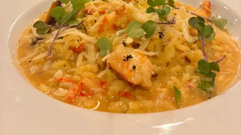 Risoto cremoso com frutos do mar e microverdes em prato branco no restaurante La Cuisine, Punta Arenas