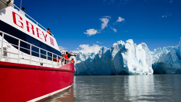 Un enorme iceberg azul flota en el lago Grey, con el campo de hielo del glaciar visible a lo lejos.