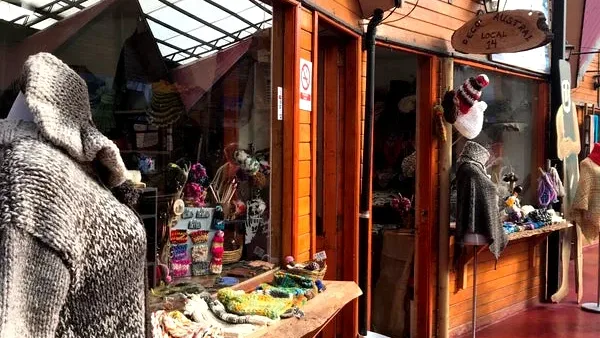 Bancas rústicas de madeira e artesanato local na Vila de Artesãos Ether Aike, em Puerto Natales.