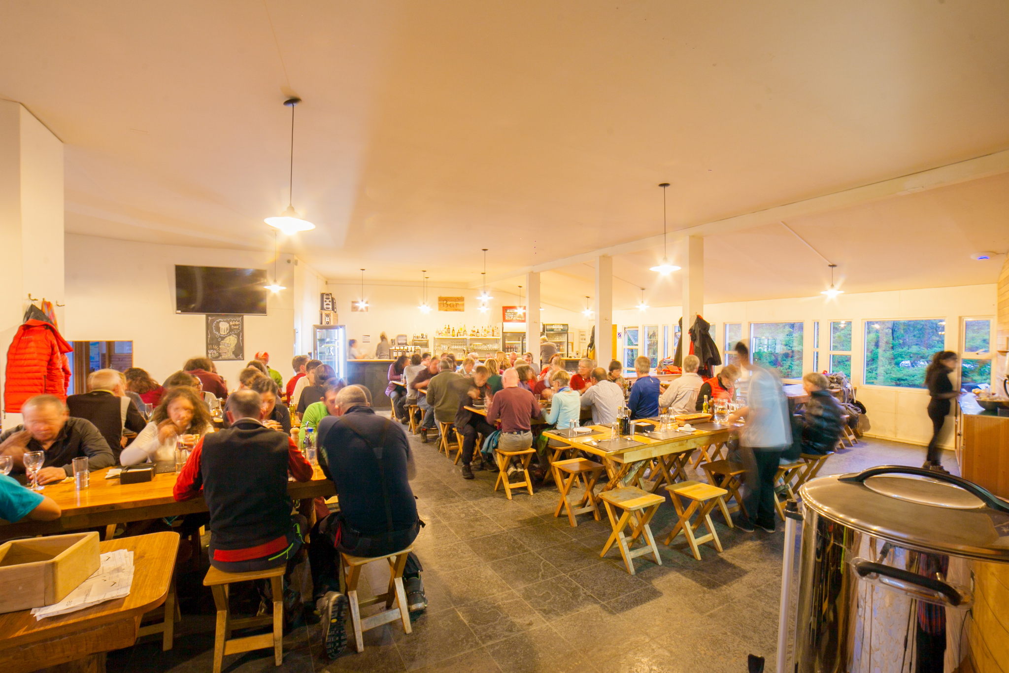 Interior luminoso e arejado do lobby central do Refugio Torres, com tetos altos de madeira.
