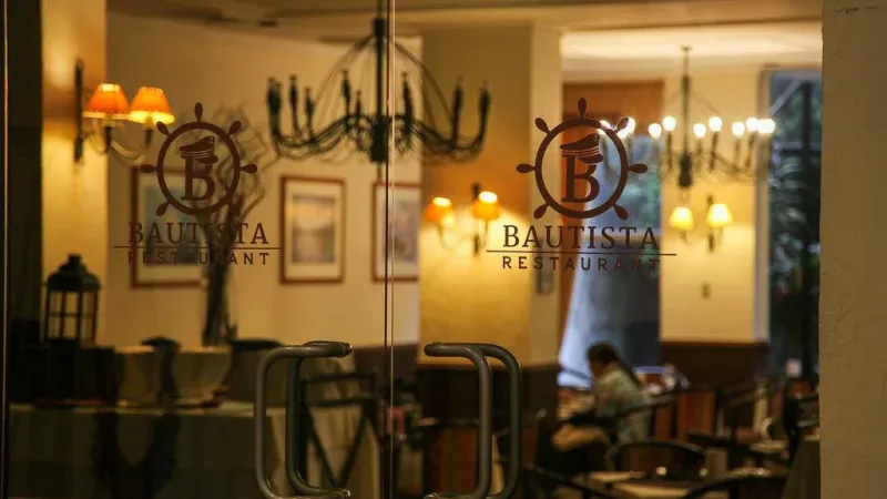The warm and inviting interior of Restaurant Bautista, featuring large windows and mountain views.