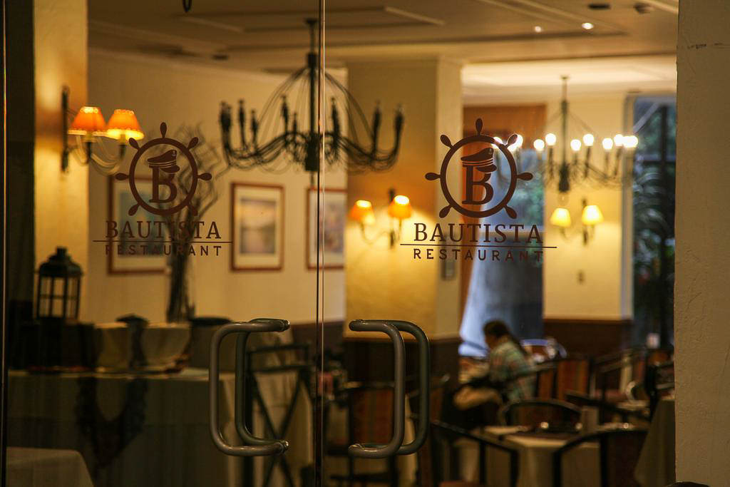 The warm and inviting interior of Restaurant Bautista, featuring large windows and mountain views.