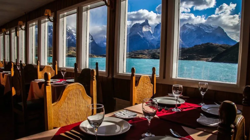 Interior of Restaurant Pehoé with large windows framing the stunning Paine Horns.