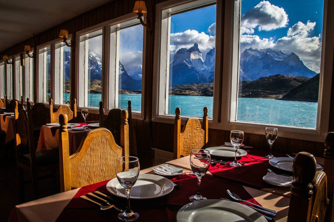 Interior del restaurante Pehoé con grandes ventanales que enmarcan las impresionantes formaciones rocosas de Paine Horns.