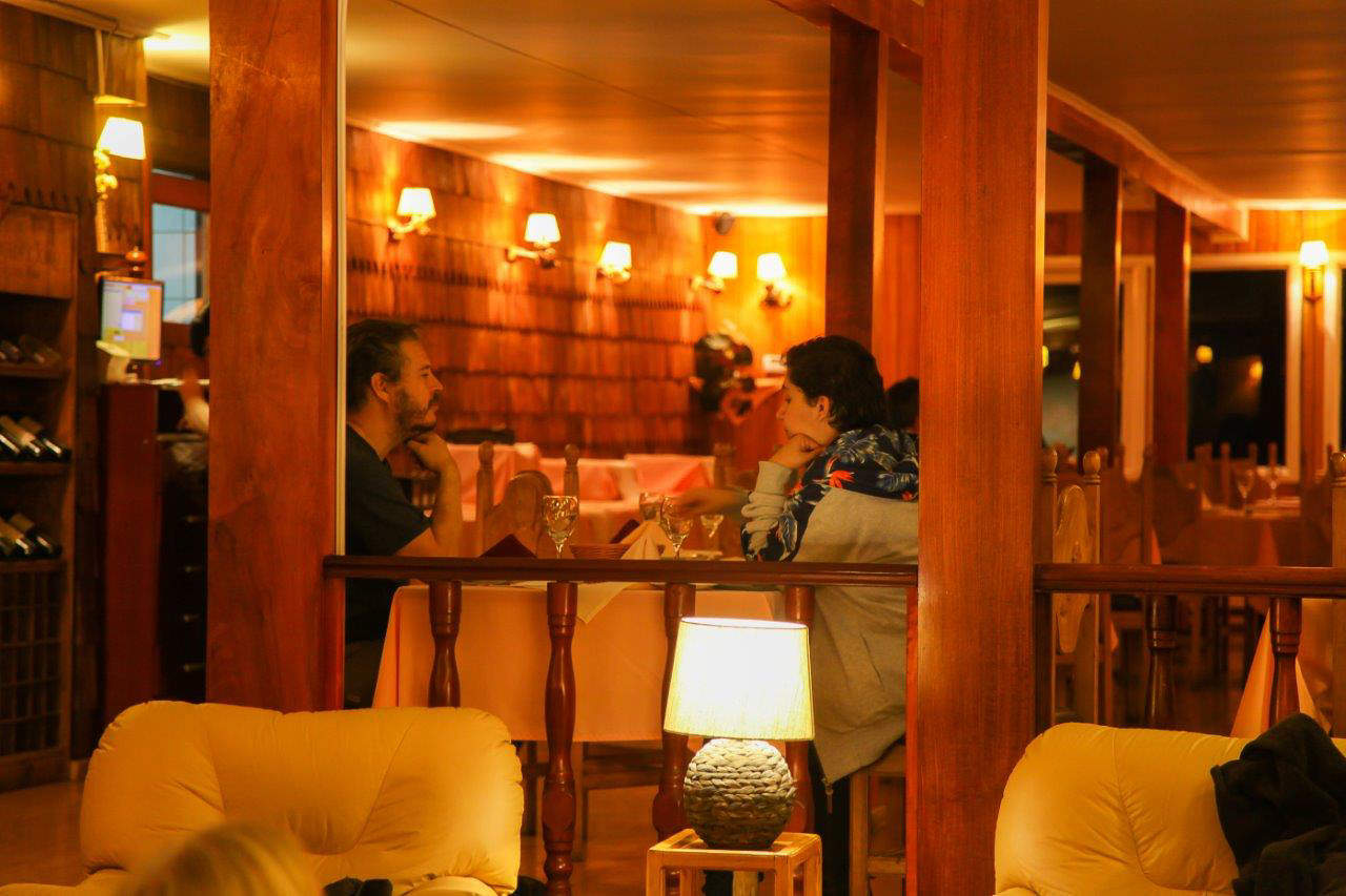 Una tranquila escena matutina en la terraza del restaurante Pehoé, con el lago reflejando las montañas.