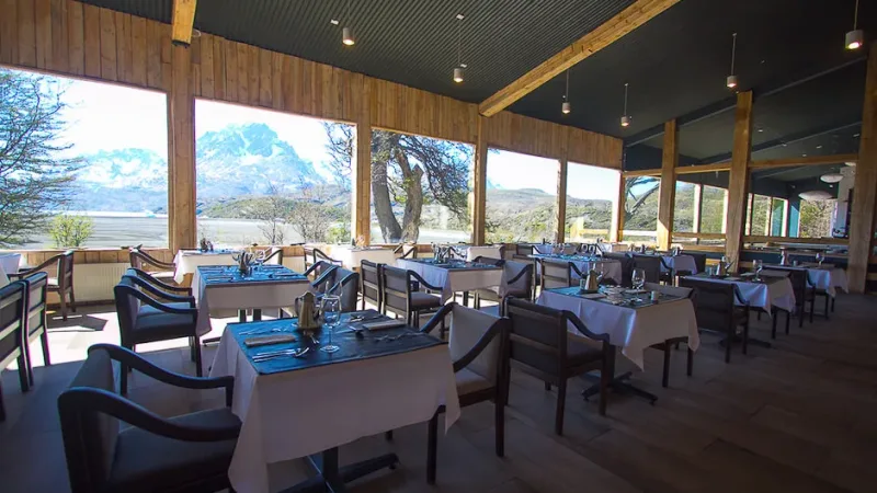 O interior aconchegante de madeira do restaurante à noite, iluminado por uma luz ambiente suave.
