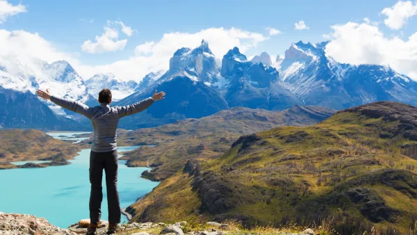 A man hiking on a rocky ridge at Mirador Condor with a panoramic view of the park behind him.
