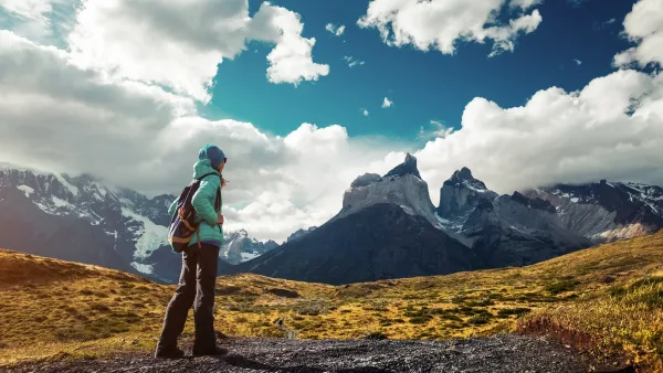 Un excursionista solitario recorre un estrecho sendero de tierra con los majestuosos picos de granito alzándose imponentes ante él.