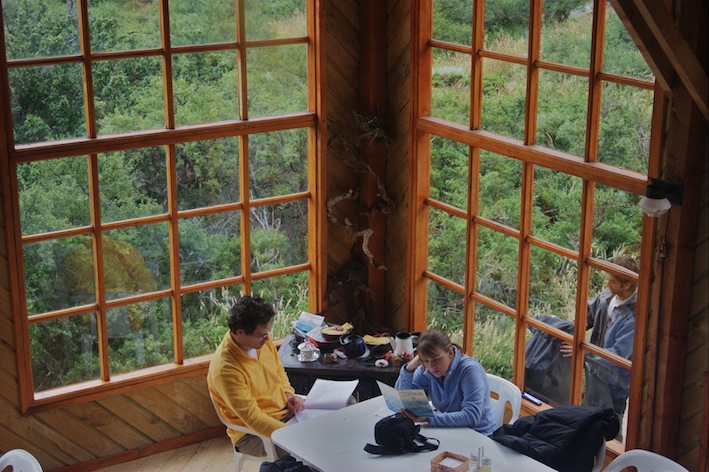 The rustic A-frame cabins and main lodge of Refugio Los Cuernos by the lake.