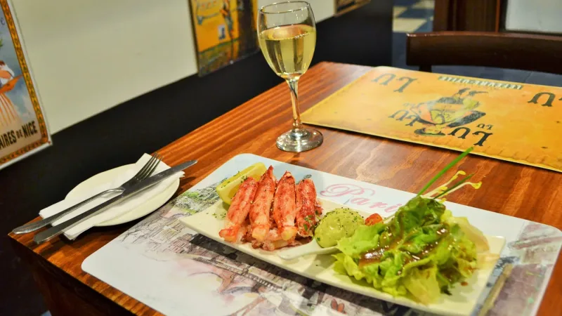 Mesas postas com toalhas de linho branco no ambiente rústico-chique do restaurante La Cuisine.