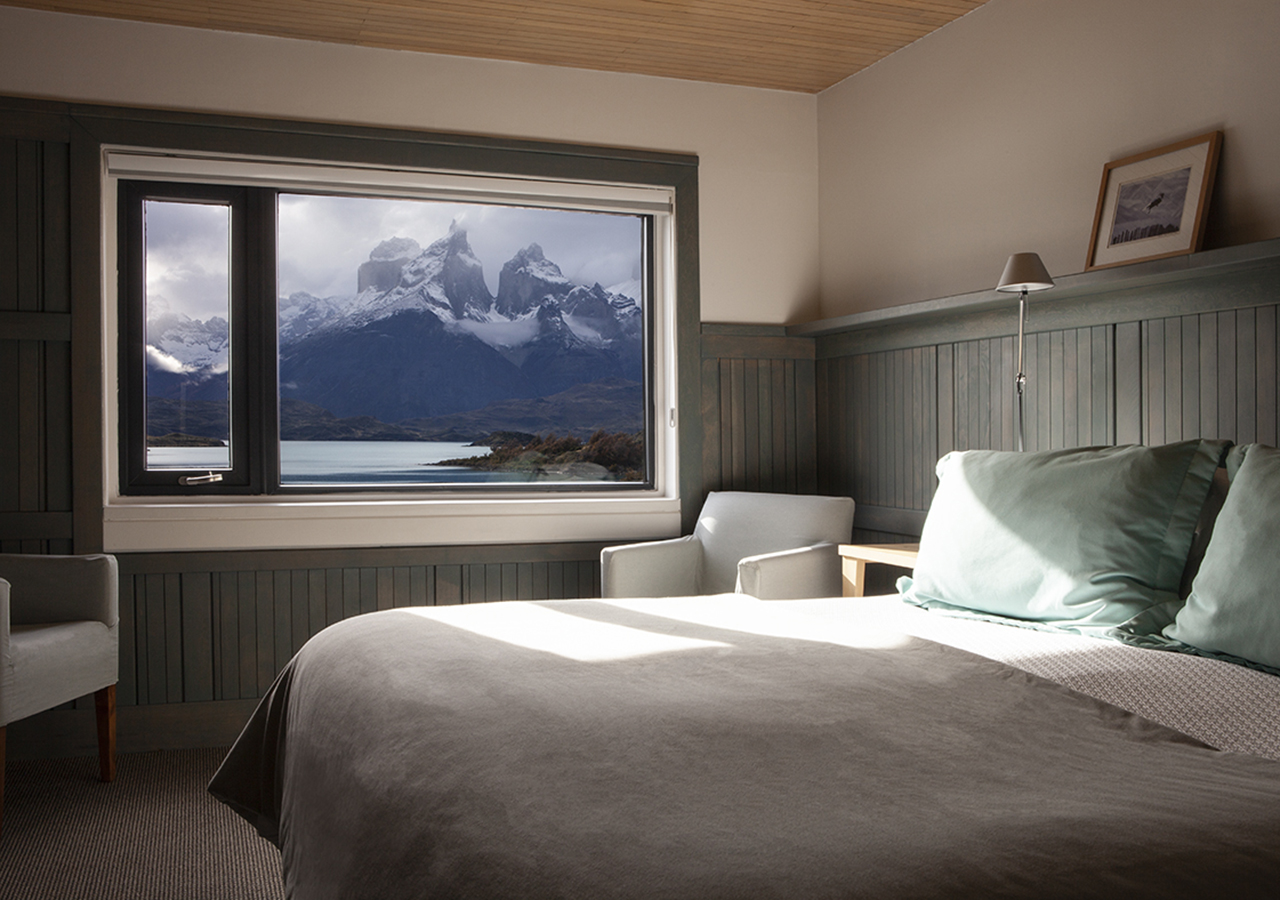 Una suite de lujo con cama king-size en el Hotel Explora, con una ventana que da directamente a los Cuernos del Paine.