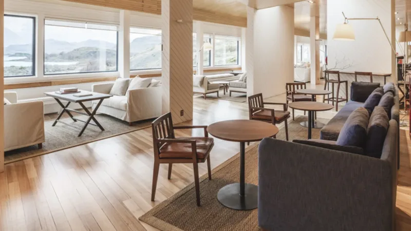 A área de estar do hotel apresenta amplas paredes de vidro e assentos modernos e confortáveis.