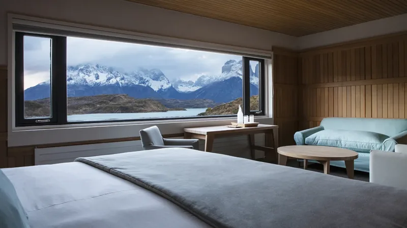 Uma espaçosa suíte de luxo no Hotel Explora, com cama king-size e grandes janelas com vista para o maciço.