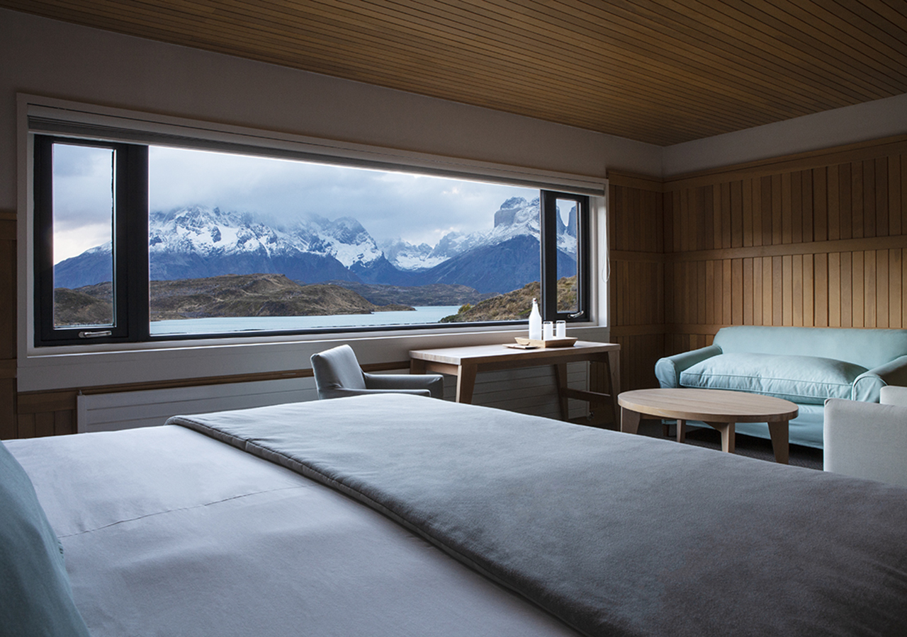 Una espaciosa suite de lujo en el Hotel Explora que cuenta con una cama tamaño king y grandes ventanales con vistas al macizo.