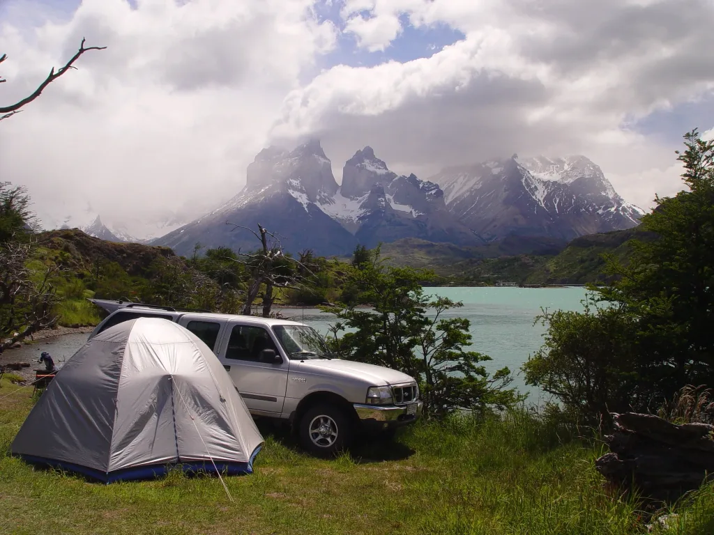 Una hilera de coloridas tiendas de campaña instaladas en una zona de acampada designada y rodeada de montañas.