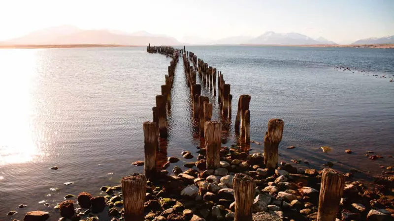 As vastas e profundas águas azuis do fiorde Seno Última Esperanza, cercadas por montanhas.