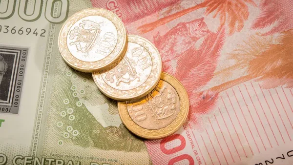 Primer plano de billetes y monedas de peso chileno, la moneda local.