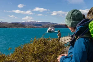 Pasajeros en la cubierta del barco Pehoé con los Cuernos del Paine al fondo.